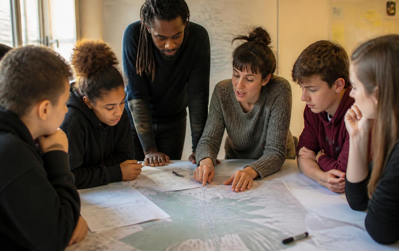 Educators and young people working together around a shared table.